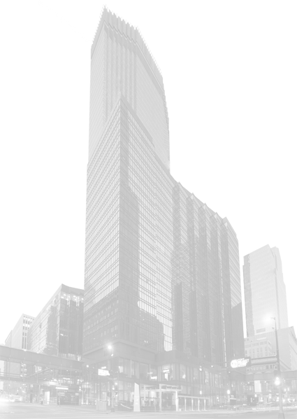 The image shows a tall, modern skyscraper with reflective windows, situated in an urban environment with other buildings around it.