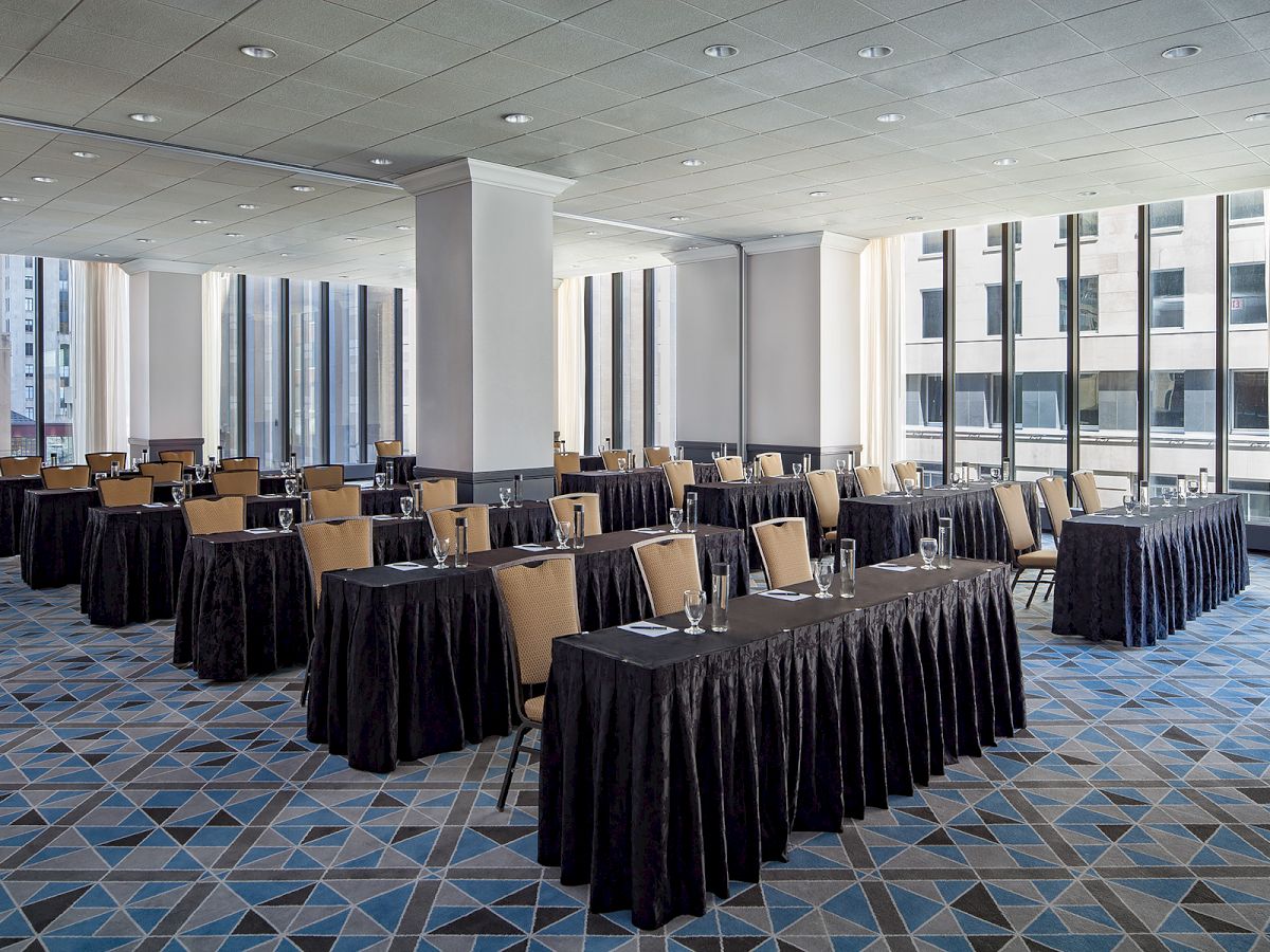 The image shows a modern conference room set up for a meeting or training session, with tables, chairs, and glasses of water arranged neatly.