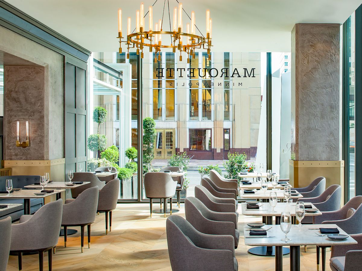 The image shows a modern restaurant with elegant seating, large windows, and a chandelier. The name "Margutta" is visible on the glass window.