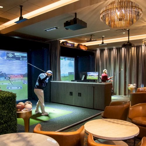 A person is playing indoor golf in a lounge with screens simulating a course, surrounded by modern seating and lighting.
