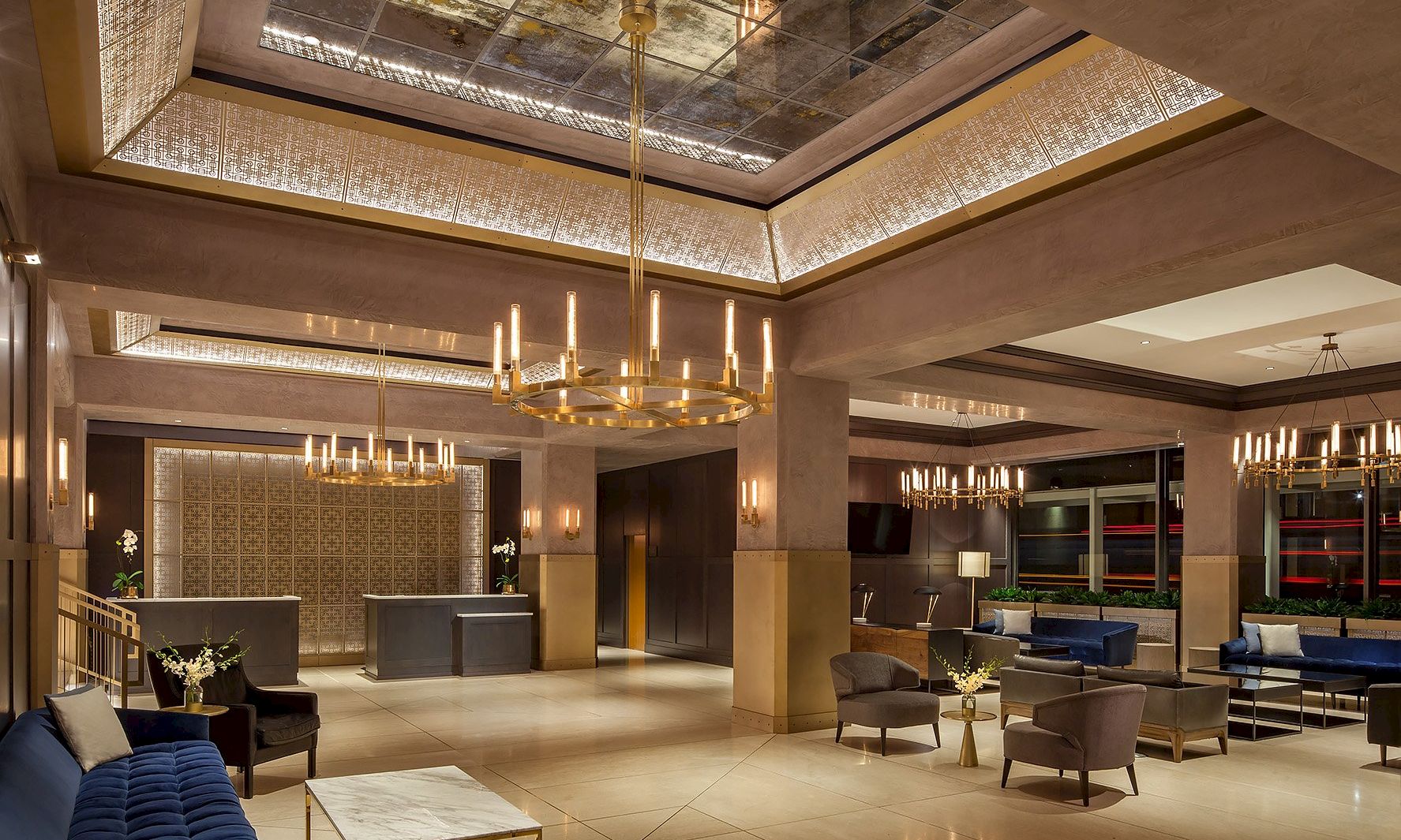 A luxurious hotel lobby with elegant chandeliers, contemporary furniture, and comfortable seating areas, featuring a reception desk and warm lighting.