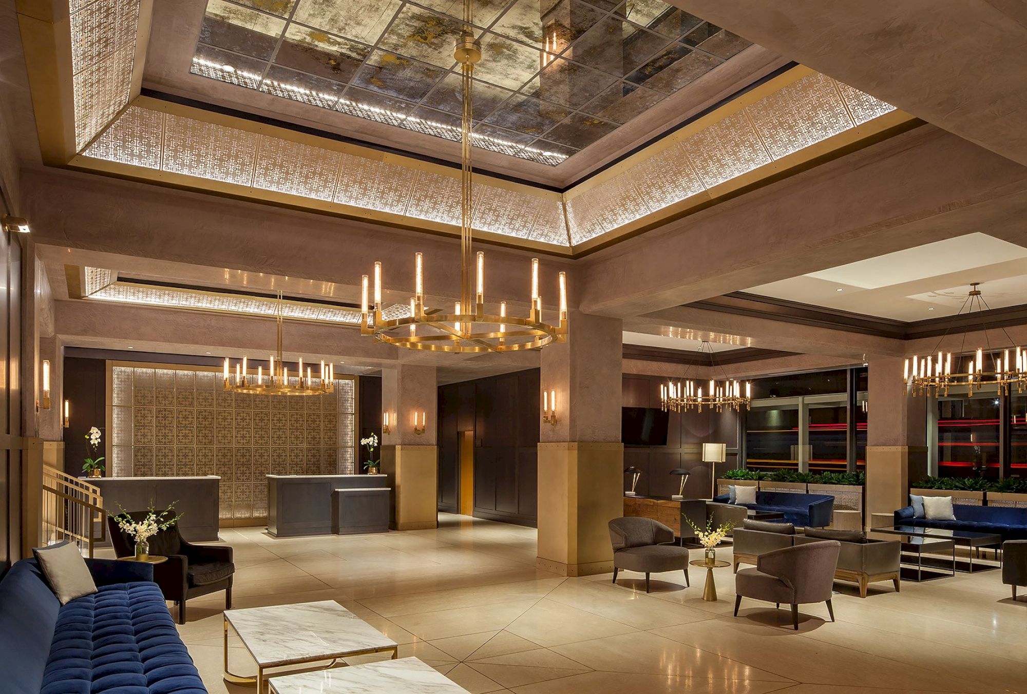 A luxurious hotel lobby with elegant chandeliers, contemporary furniture, and comfortable seating areas, featuring a reception desk and warm lighting.