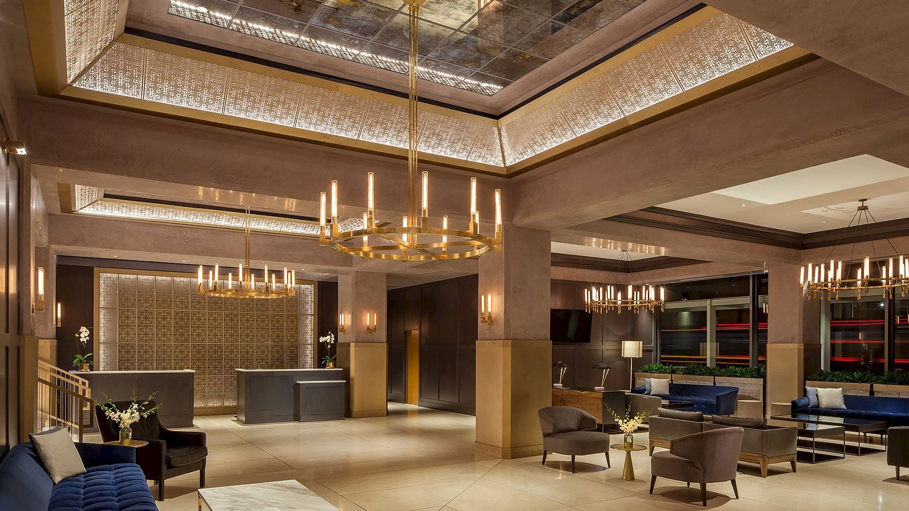 A spacious, luxurious lobby with modern chandeliers, seating areas, and a front desk in a stylish, well-lit environment ending the sentence.