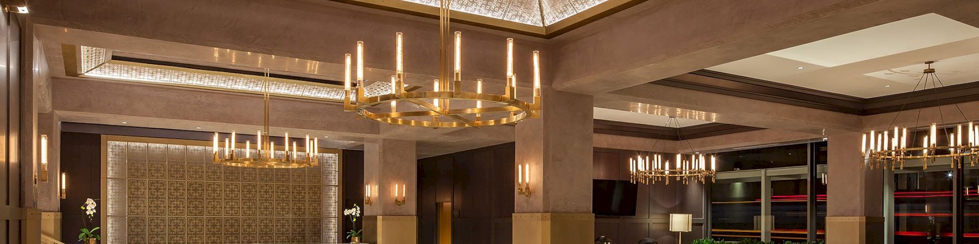 A spacious, luxurious lobby with modern chandeliers, seating areas, and a front desk in a stylish, well-lit environment ending the sentence.