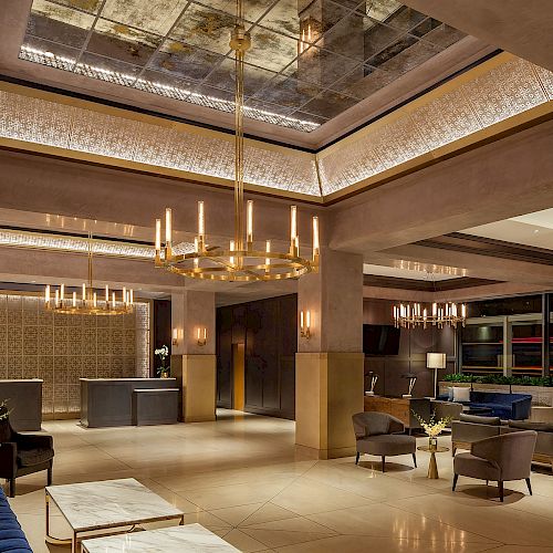 This image shows a luxurious hotel lobby with elegant chandeliers, comfortable seating areas, and a modern reception desk, creating a welcoming ambiance.